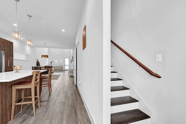 stairs with recessed lighting, wood finish floors, and baseboards