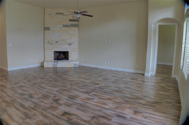 3054 Choke Canyon Ln, League City, TX 77573 - unfurnished living room with arched walkways, plenty of natural light, a ceiling fan, wood finished floors, and a fireplace