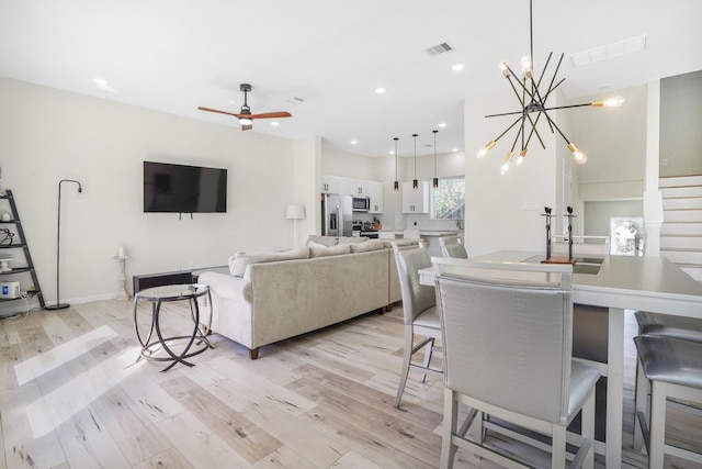 living room with recessed lighting, ceiling fan with notable chandelier, visible vents, and light wood-type flooring