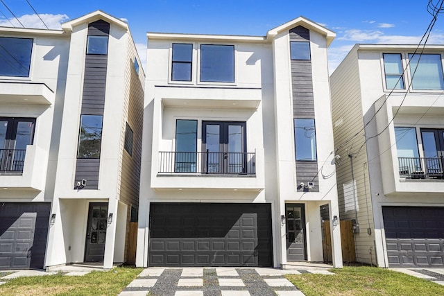 view of property featuring stucco siding, french doors, a balcony, and a garage