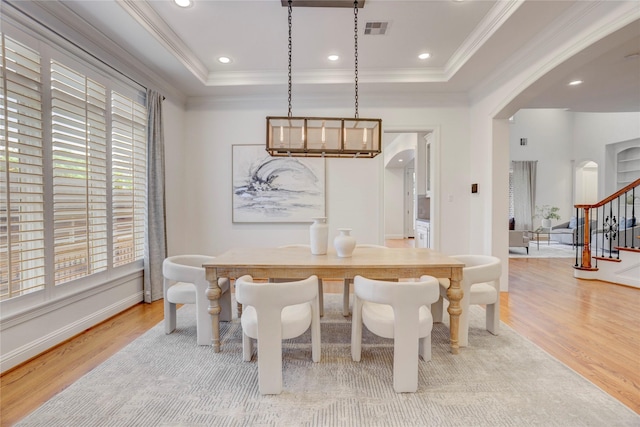 dining space with arched walkways, wood finished floors, visible vents, and ornamental molding