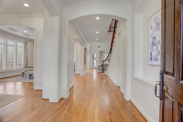 foyer with arched walkways, a wealth of natural light, and light wood finished floors