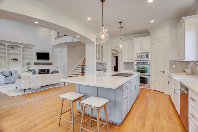 kitchen with a kitchen breakfast bar, stainless steel appliances, a kitchen island, a fireplace, and white cabinetry