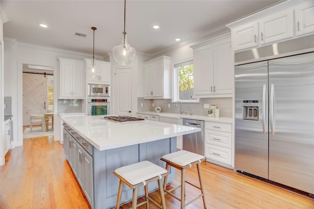 kitchen with crown molding, decorative backsplash, built in appliances, white cabinets, and visible vents