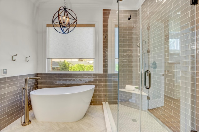 bathroom with a shower stall, a notable chandelier, a freestanding tub, and tile walls
