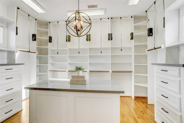 walk in closet featuring light wood-type flooring, visible vents, and an inviting chandelier