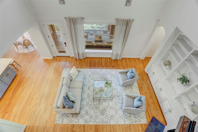 living room featuring arched walkways, wood finished floors, visible vents, and baseboards