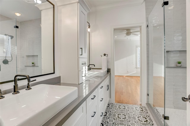full bathroom featuring a shower stall, ceiling fan, crown molding, and a sink