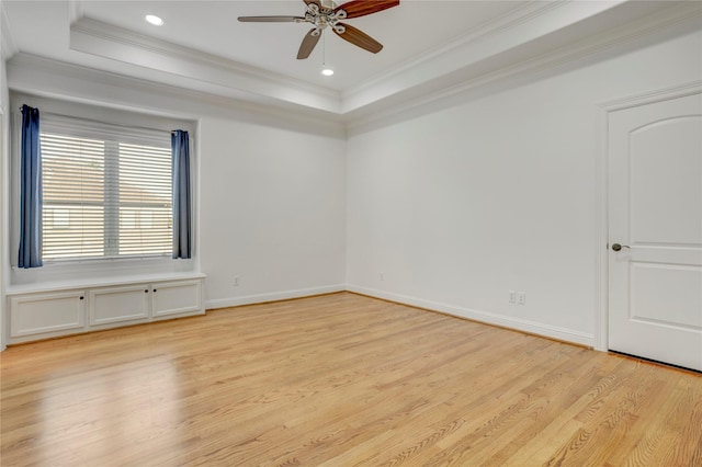 spare room featuring a tray ceiling, light wood-type flooring, and ornamental molding