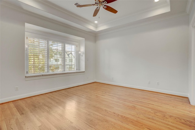 spare room with a tray ceiling, crown molding, wood finished floors, and a ceiling fan