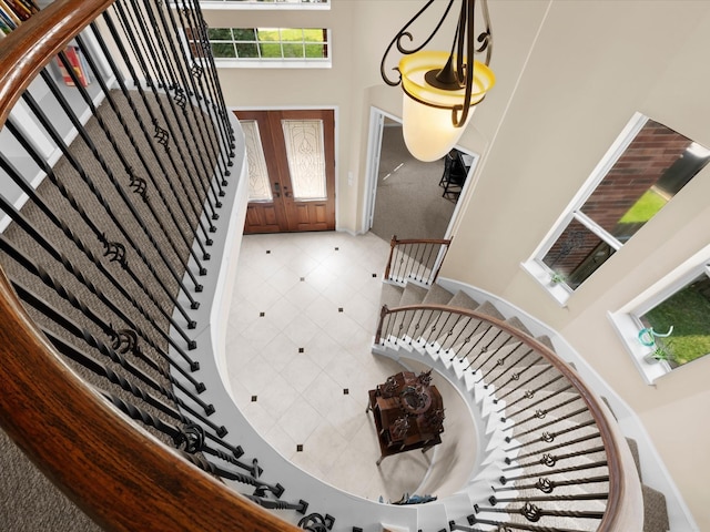 tiled entrance foyer with stairway, baseboards, and a high ceiling