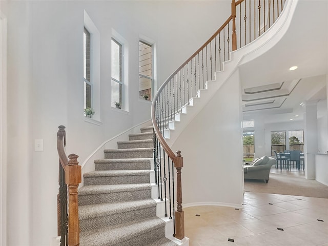 staircase with tile patterned floors, baseboards, recessed lighting, and a towering ceiling