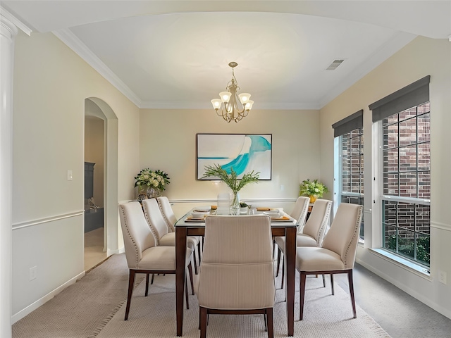 carpeted dining space with an inviting chandelier, arched walkways, baseboards, and visible vents