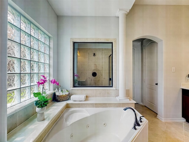 full bath featuring tile patterned flooring, vanity, a jetted tub, decorative columns, and a stall shower