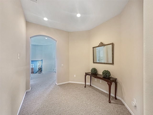 hallway with arched walkways, baseboards, recessed lighting, and carpet