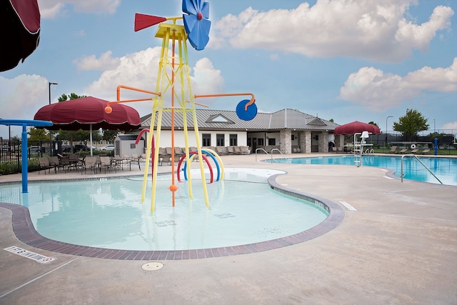 community pool featuring fence, a patio area, and a water play area