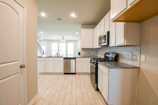 2103 Islawild Way, Texas City, TX 77568 - kitchen featuring appliances with stainless steel finishes, a sink, dark stone countertops, a ceiling fan, and tasteful backsplash