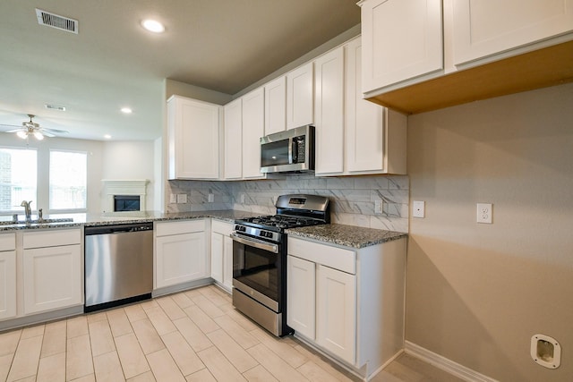 2103 Islawild Way, Texas City, TX 77568 - kitchen featuring stainless steel appliances, a sink, ceiling fan, decorative backsplash, and dark stone counters