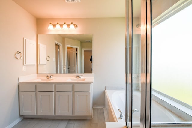 2103 Islawild Way, Texas City, TX 77568 - bathroom with a garden tub, wood finished floors, double vanity, and baseboards