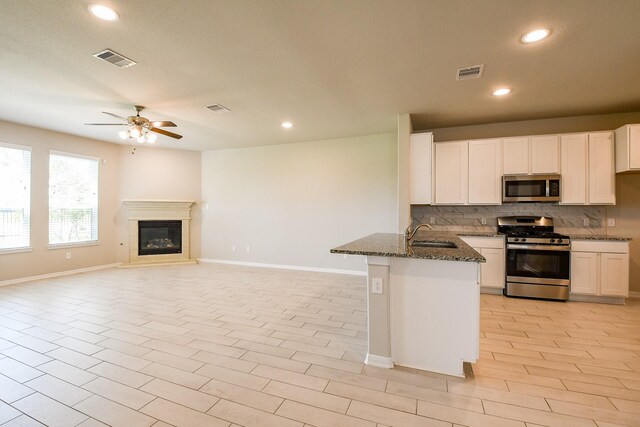 2103 Islawild Way, Texas City, TX 77568 - kitchen featuring stainless steel appliances, a sink, dark stone countertops, decorative backsplash, and baseboards