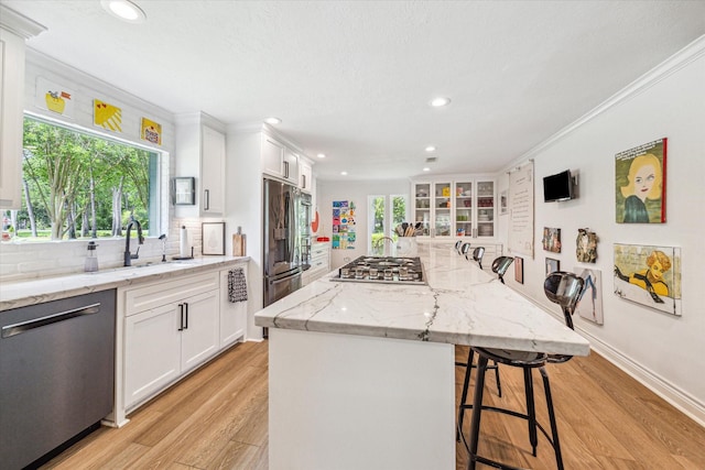 kitchen featuring white cabinets, a breakfast bar area, stainless steel appliances, backsplash, and recessed lighting