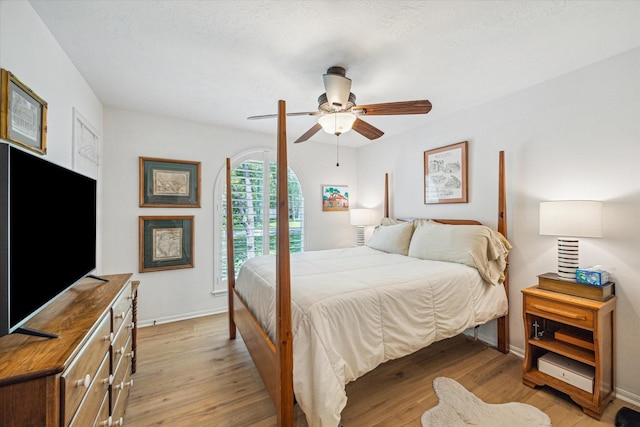bedroom with light wood finished floors, baseboards, and a ceiling fan