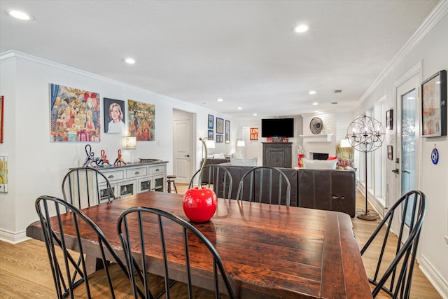 dining room with recessed lighting, light wood-style floors, a brick fireplace, and ornamental molding