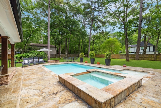 view of pool with a pool with connected hot tub, a patio area, a lawn, and a fenced backyard