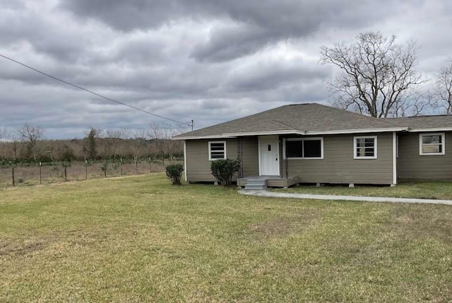 view of front of house featuring fence, a shingled roof, and a front yard