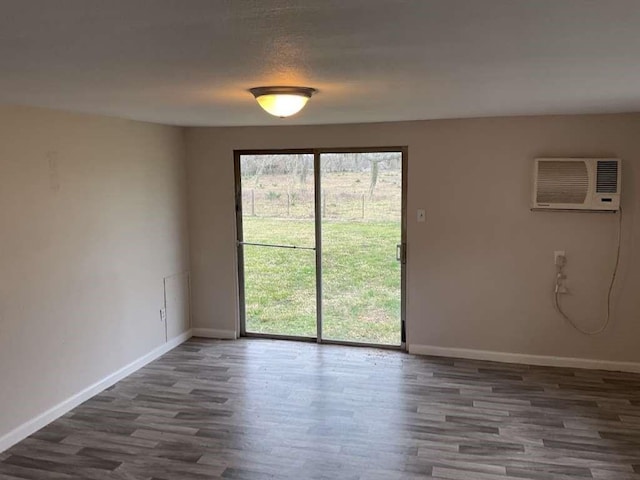 empty room featuring baseboards, wood finished floors, and a wall unit AC