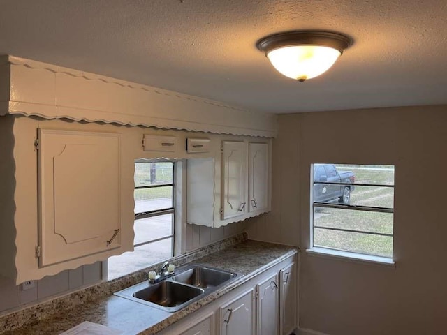 kitchen with white cabinetry, a sink, and a textured ceiling