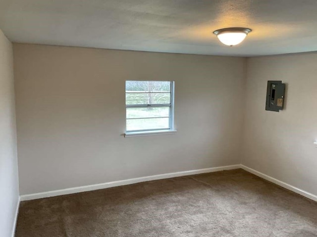 spare room featuring carpet floors, electric panel, and baseboards