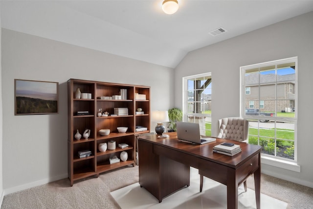office area with baseboards, vaulted ceiling, visible vents, and light colored carpet