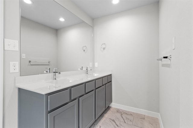 bathroom with marble finish floor, baseboards, a sink, and recessed lighting