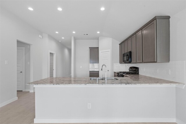 369 Spruce Oak Ln, Waller, TX 77484 - kitchen with a sink, gas range oven, black microwave, recessed lighting, and tasteful backsplash