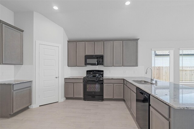 369 Spruce Oak Ln, Waller, TX 77484 - kitchen featuring black appliances, a sink, a peninsula, gray cabinetry, and vaulted ceiling