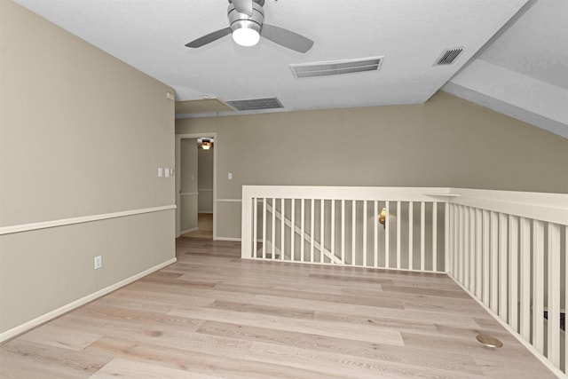 additional living space with ceiling fan, attic access, wood finished floors, and visible vents