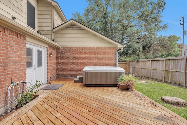 deck with a hot tub, french doors, and a fenced backyard