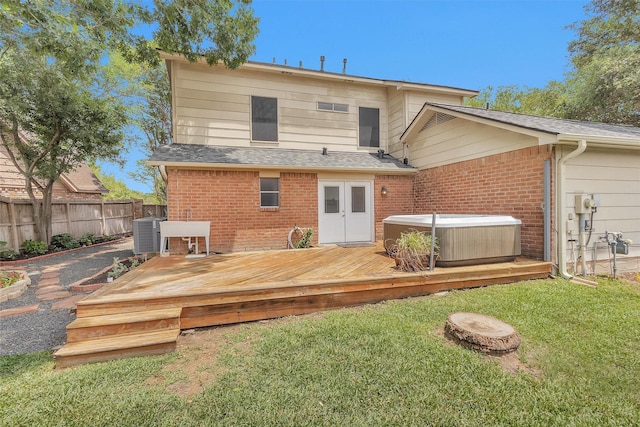 back of property featuring fence, a wooden deck, a hot tub, and brick siding
