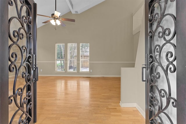foyer with baseboards, lofted ceiling with beams, light wood-style flooring, and a ceiling fan