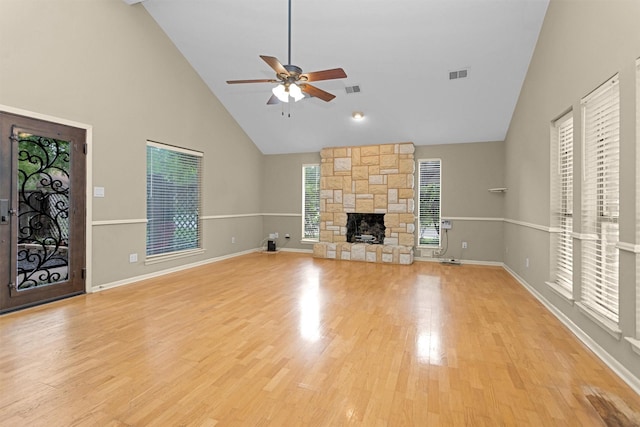 unfurnished living room featuring visible vents, a stone fireplace, high vaulted ceiling, light wood-type flooring, and a ceiling fan