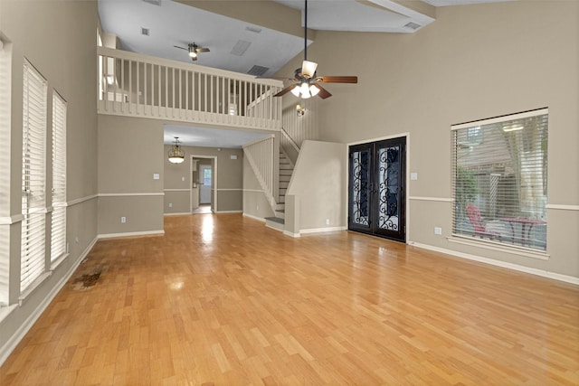 unfurnished living room featuring stairs, wood finished floors, baseboards, ceiling fan, and high vaulted ceiling