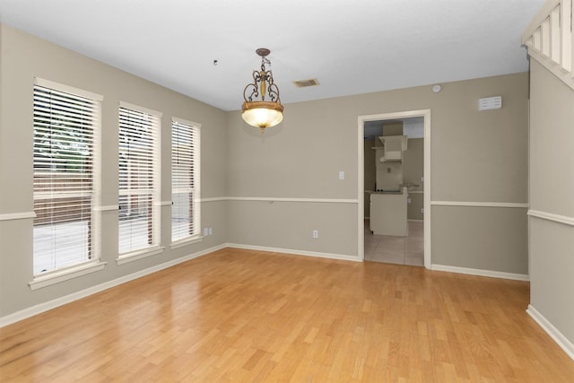 empty room with visible vents, light wood-style flooring, and baseboards