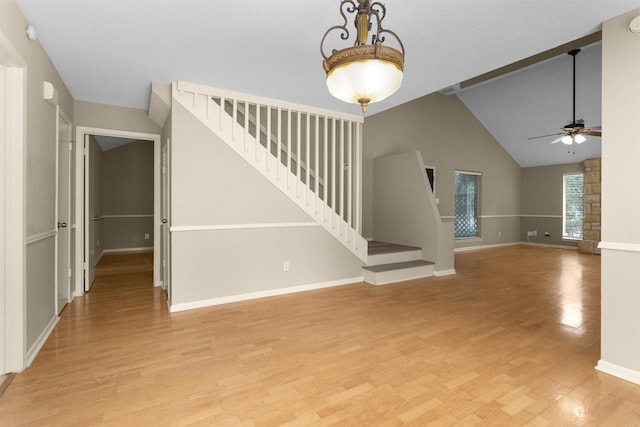 unfurnished living room featuring light wood-type flooring, a ceiling fan, stairs, and baseboards