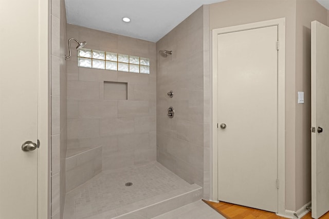 full bathroom featuring wood finished floors and tiled shower