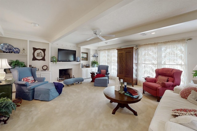 living area featuring beam ceiling, a brick fireplace, carpet floors, and ceiling fan