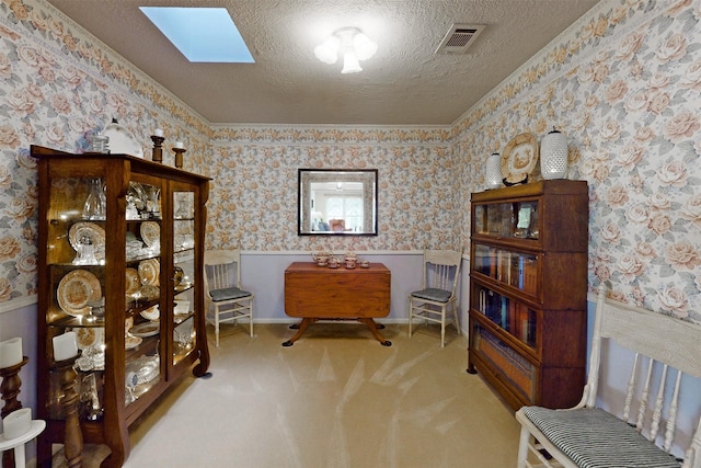 living area with wallpapered walls, a textured ceiling, a wainscoted wall, and a skylight