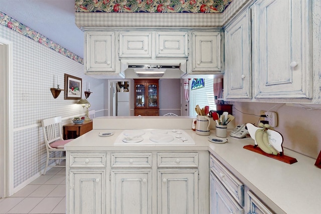 kitchen featuring a peninsula, light countertops, wallpapered walls, and light tile patterned floors