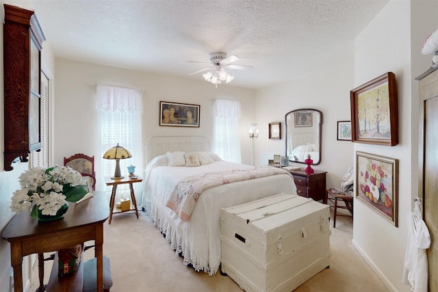 bedroom with a textured ceiling, a ceiling fan, and light carpet