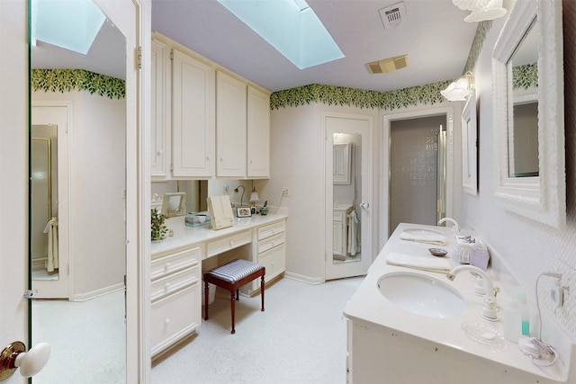 bathroom with baseboards, visible vents, a skylight, and vanity